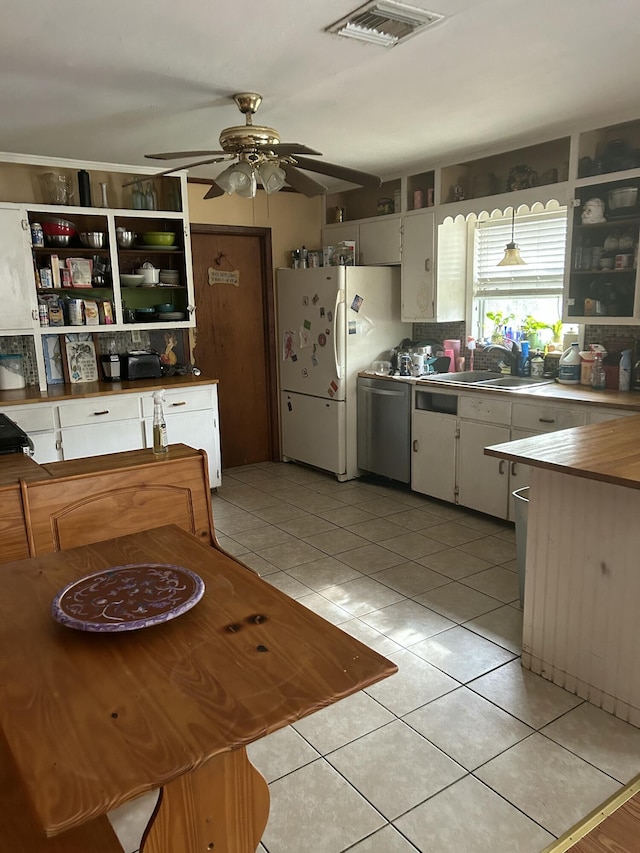 kitchen with stainless steel dishwasher, white cabinets, sink, and light tile patterned floors