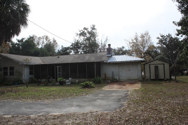 view of front of house featuring a garage, a sunroom, and a storage unit