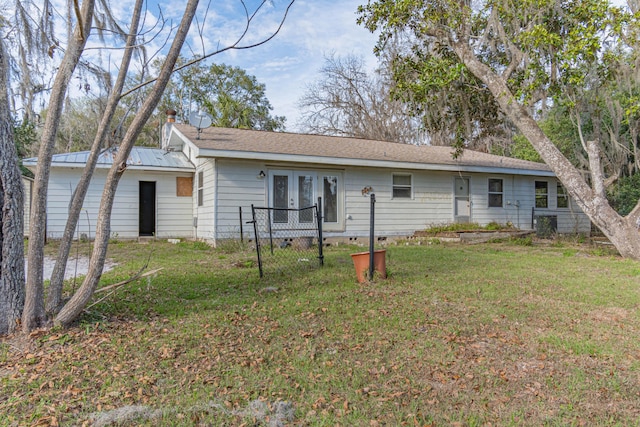 rear view of property with french doors and a yard