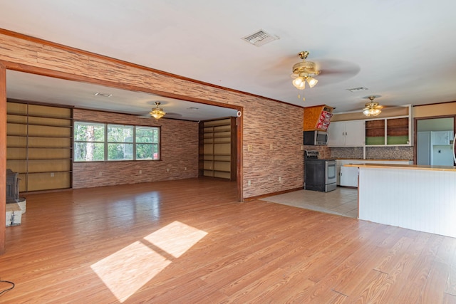 unfurnished living room with ornamental molding, a wood stove, ceiling fan, and light hardwood / wood-style flooring