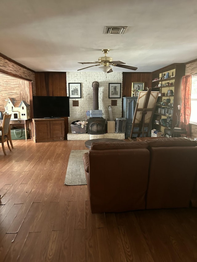 living room with ceiling fan, dark hardwood / wood-style flooring, and a wood stove