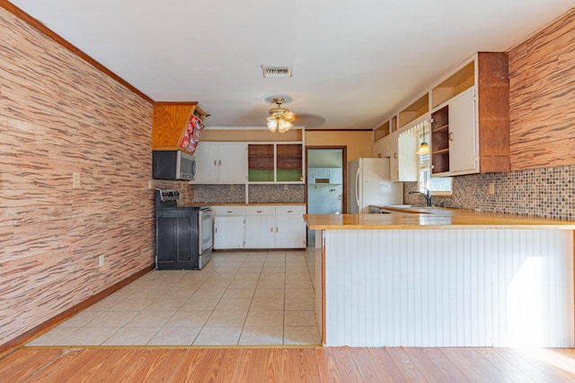 kitchen featuring tasteful backsplash, stainless steel appliances, sink, white cabinetry, and kitchen peninsula