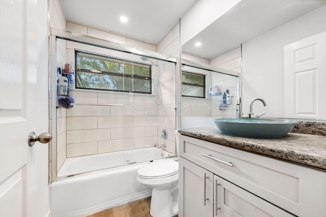 full bathroom with vanity, hardwood / wood-style floors, shower / bath combination with glass door, and toilet