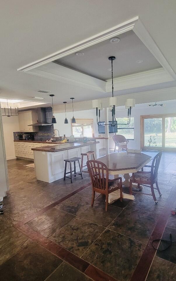 dining area with a raised ceiling, a wealth of natural light, and crown molding