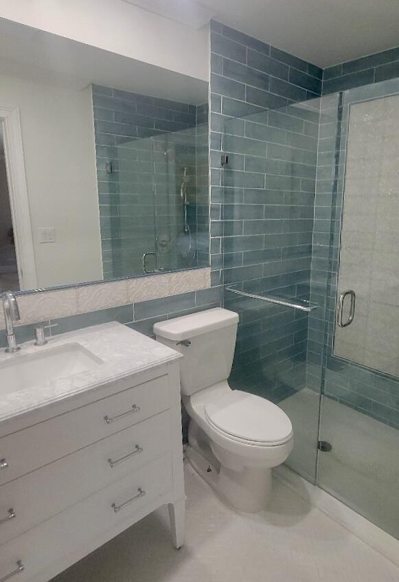 bathroom with tile walls, toilet, walk in shower, and vanity