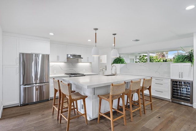 kitchen with white cabinetry, stainless steel fridge, wine cooler, hanging light fixtures, and sink