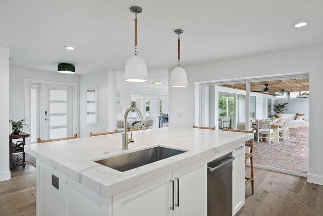 kitchen with sink, pendant lighting, white cabinets, and a kitchen island with sink