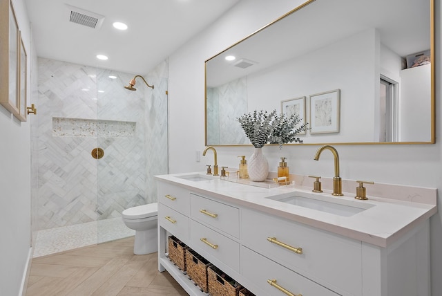 bathroom with toilet, tiled shower, and vanity