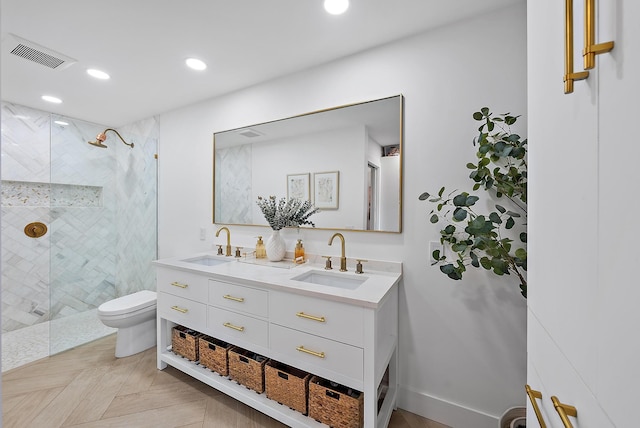 bathroom featuring toilet, vanity, parquet flooring, and tiled shower