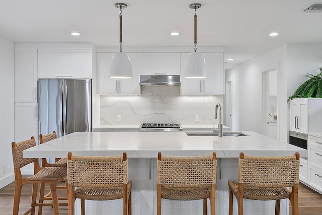 kitchen with pendant lighting, sink, a kitchen island with sink, dark wood-type flooring, and white cabinets