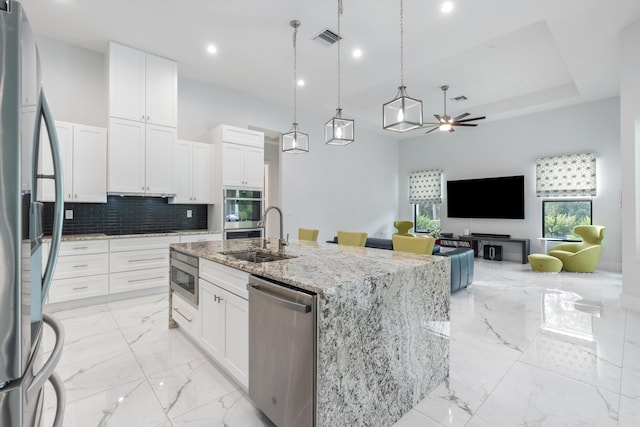 kitchen with decorative light fixtures, white cabinetry, an island with sink, sink, and stainless steel appliances