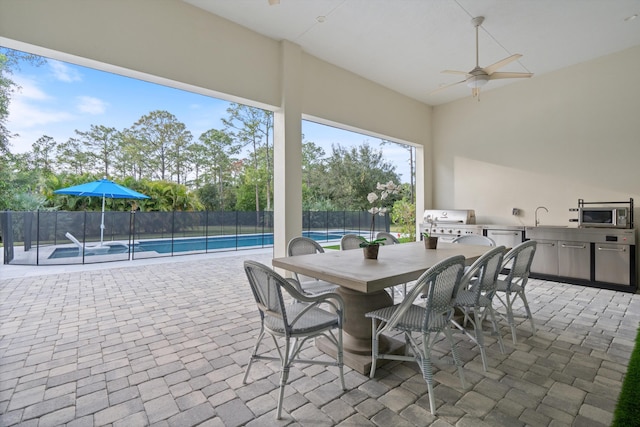 view of patio featuring an outdoor kitchen, sink, ceiling fan, a grill, and a fenced in pool