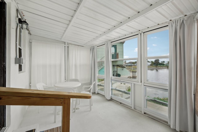 sunroom with vaulted ceiling and a water view