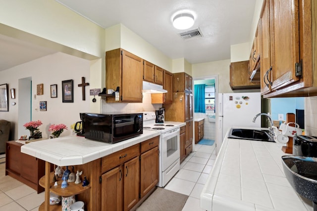 kitchen with light tile patterned floors, tile countertops, sink, refrigerator, and white electric stove