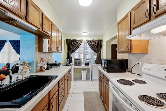 kitchen featuring light tile patterned floors, decorative backsplash, electric range, and sink