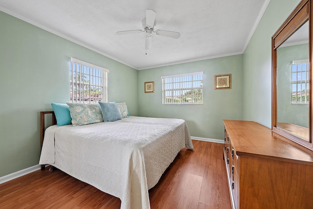 bedroom featuring multiple windows, ornamental molding, dark wood-type flooring, and ceiling fan