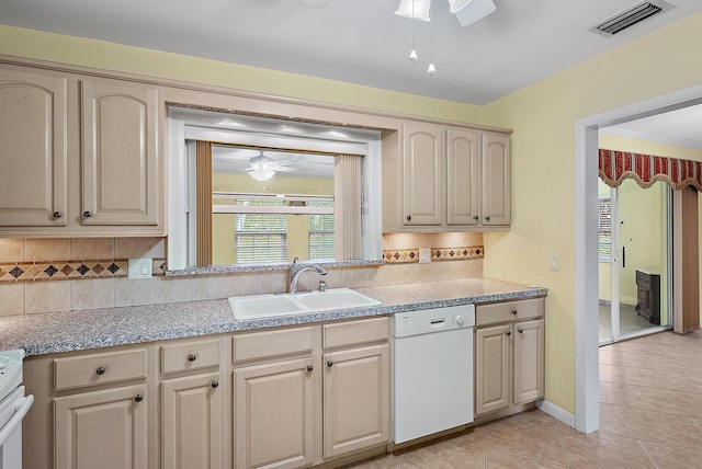 kitchen with white dishwasher, a sink, decorative backsplash, ceiling fan, and visible vents