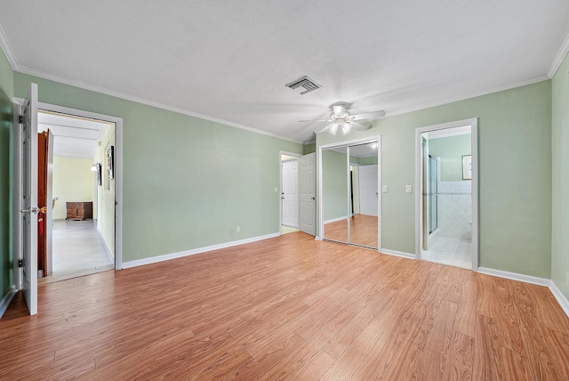 unfurnished bedroom featuring ensuite bathroom, ceiling fan, crown molding, a textured ceiling, and light hardwood / wood-style flooring