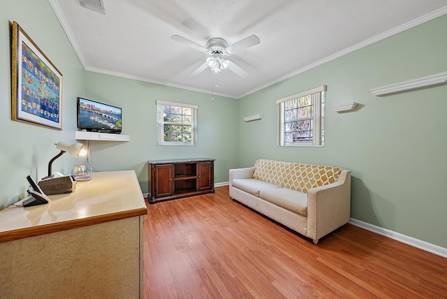living room featuring light wood-type flooring, a ceiling fan, baseboards, and crown molding