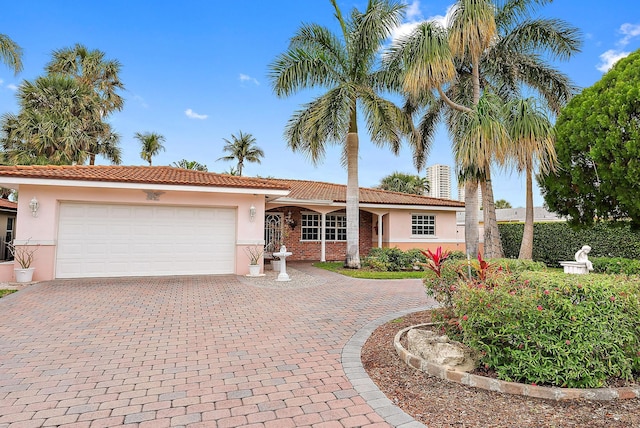 single story home with a garage, a tile roof, stucco siding, and decorative driveway