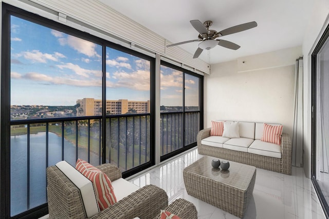 sunroom with ceiling fan and a water view