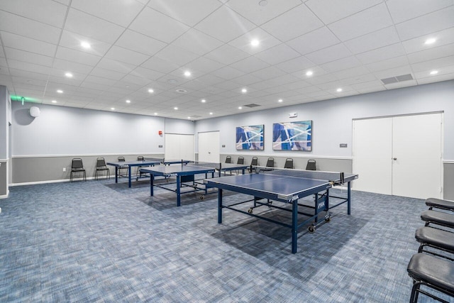 recreation room featuring a drop ceiling and carpet floors