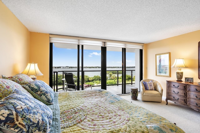 bedroom featuring a water view, carpet floors, access to exterior, and a textured ceiling