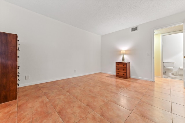 tiled empty room with a textured ceiling