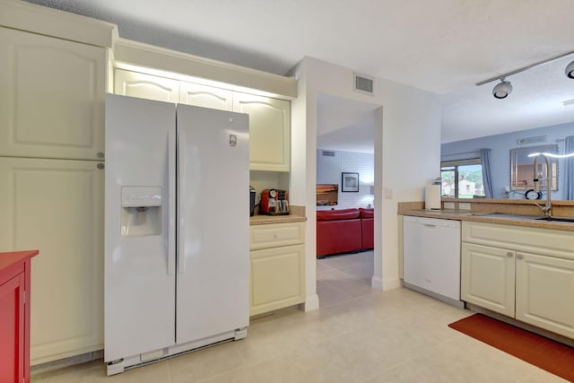 kitchen featuring sink, track lighting, white appliances, and light tile patterned floors