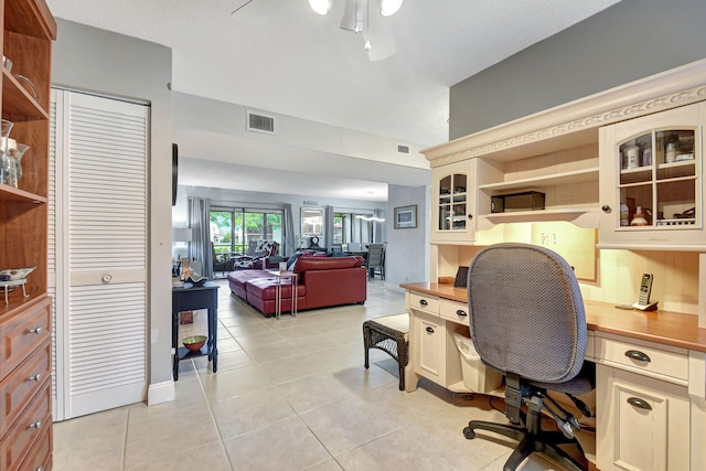 office area with built in desk, ceiling fan, and light tile patterned flooring