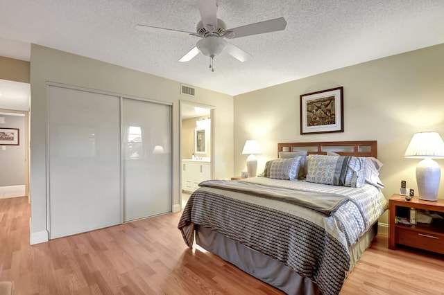 bedroom with light hardwood / wood-style flooring, a closet, ceiling fan, and ensuite bathroom