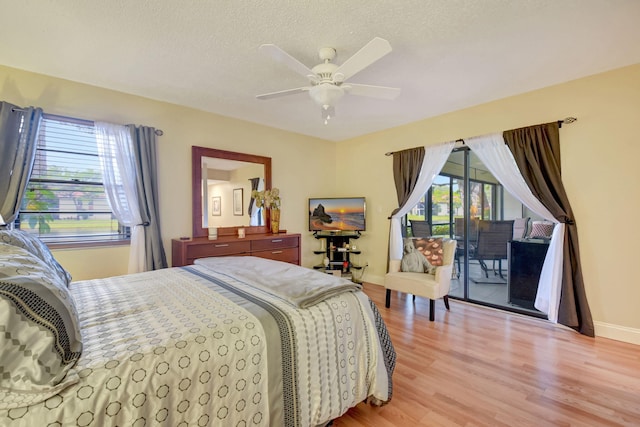 bedroom featuring multiple windows, access to outside, ceiling fan, and light wood-type flooring