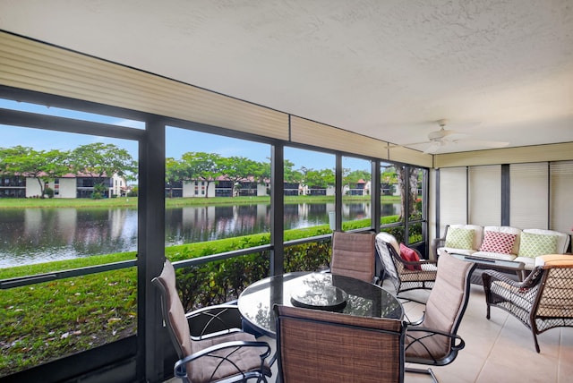 sunroom featuring ceiling fan and a water view