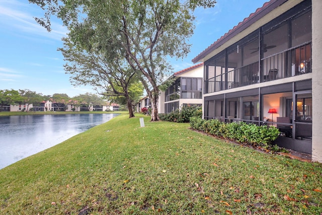 view of yard with a sunroom and a water view