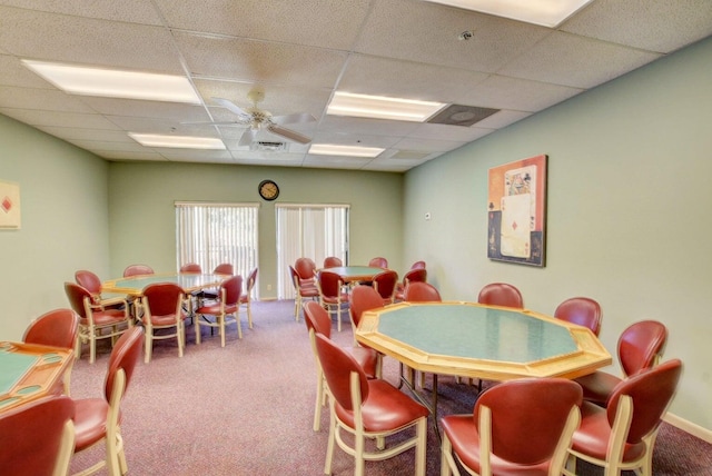 carpeted dining space with a drop ceiling and ceiling fan