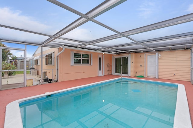 view of swimming pool featuring glass enclosure and a patio area