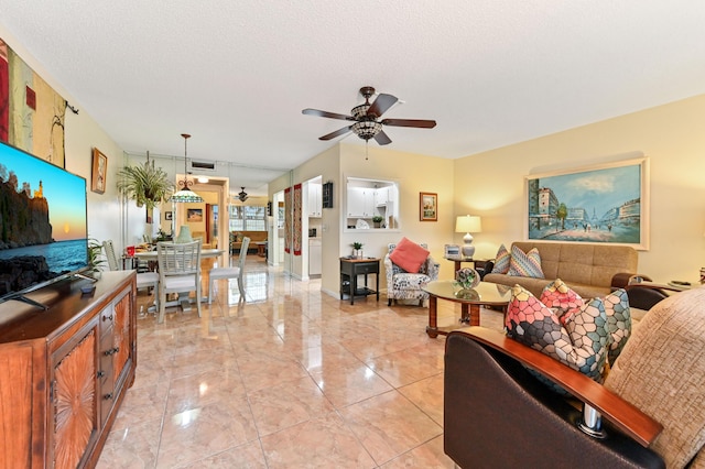 living room featuring ceiling fan and a textured ceiling