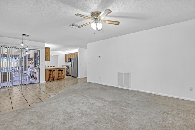 unfurnished living room with a ceiling fan, light colored carpet, visible vents, and light tile patterned floors