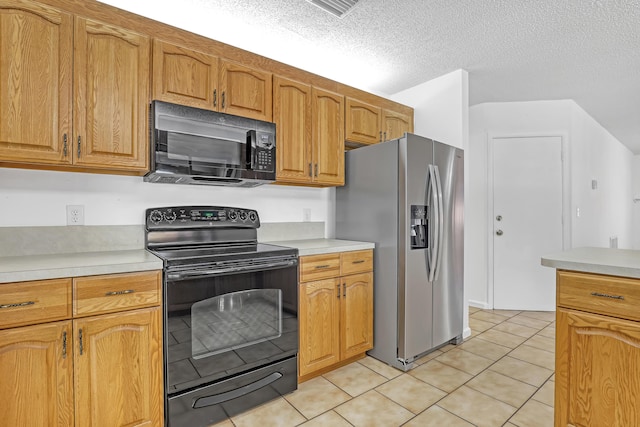 kitchen featuring a textured ceiling, light tile patterned floors, light countertops, black appliances, and brown cabinetry