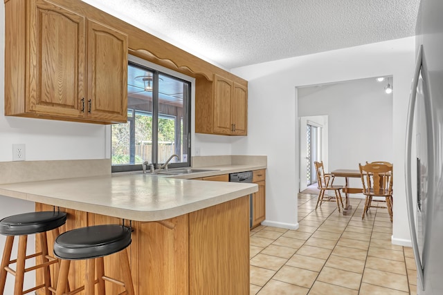 kitchen featuring light countertops, a kitchen bar, a sink, and a peninsula