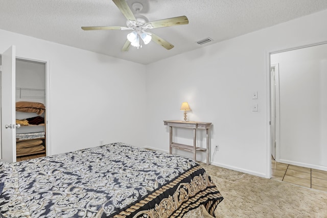 carpeted bedroom with baseboards, a spacious closet, visible vents, and a textured ceiling