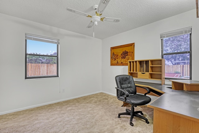 office space featuring a ceiling fan, baseboards, a textured ceiling, and light colored carpet