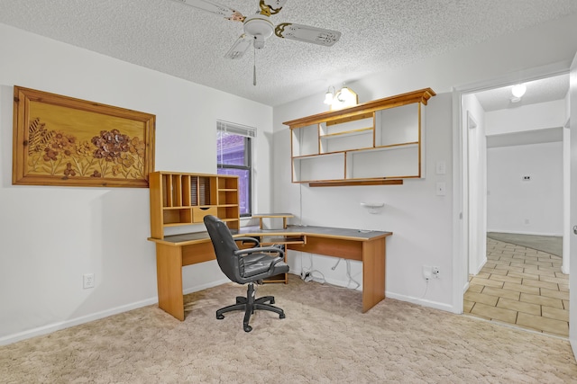 office featuring a textured ceiling, baseboards, a ceiling fan, and light colored carpet