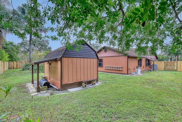 view of yard featuring a storage shed, an outbuilding, a fenced backyard, and central air condition unit