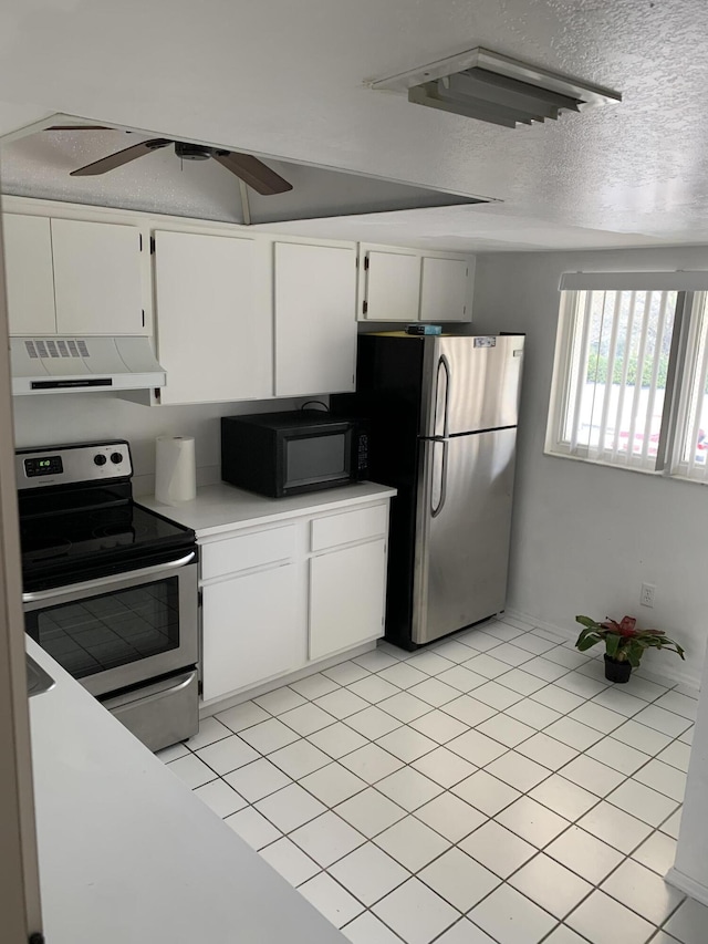 kitchen featuring light tile patterned floors, white cabinetry, extractor fan, stainless steel appliances, and a textured ceiling