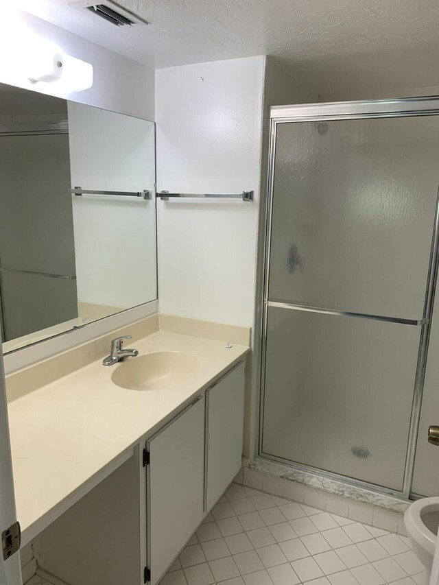 bathroom with a shower with shower door, vanity, tile patterned floors, and a textured ceiling