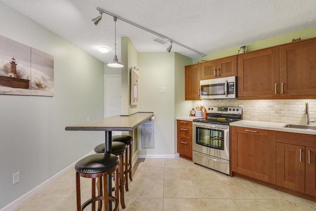 kitchen featuring stainless steel appliances, backsplash, a textured ceiling, pendant lighting, and sink