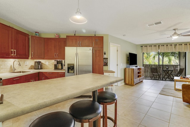 kitchen with tasteful backsplash, ceiling fan, pendant lighting, stainless steel refrigerator with ice dispenser, and light tile patterned flooring