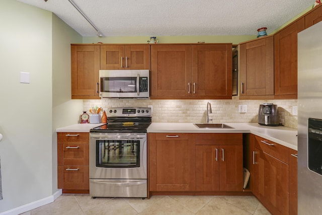 kitchen with decorative backsplash, appliances with stainless steel finishes, sink, and a textured ceiling