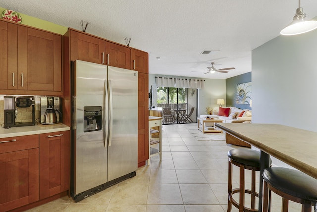 kitchen featuring a textured ceiling, decorative light fixtures, stainless steel fridge with ice dispenser, ceiling fan, and light tile patterned floors